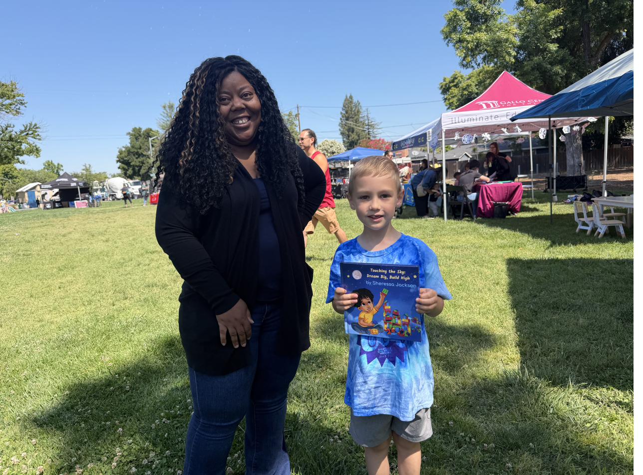 Sheressa with a young reader holding her book